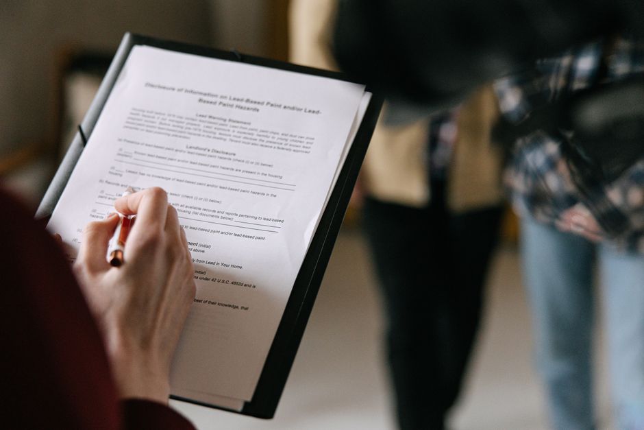 Close-up of a person's hand holding a pen and reviewing a printed document titled 'Processing of information to Landlord or Leasehold' on a clipboard during a home relocation or furniture transport pl